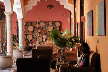 Girl waiting in a chair in a hall of an hacienda  - obrazy, fototapety, plakaty