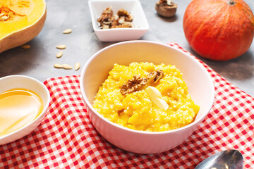 Rice milk pumpkin porridge with walnuts, butter and honey on concrete table. Healthy food.
