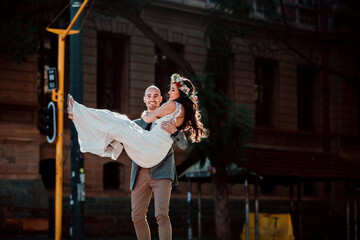 Husband carrying bride accross street in city