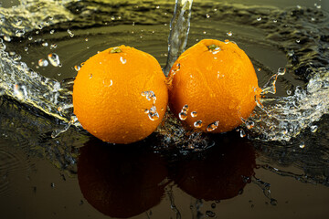 two whole oranges on dark glass with reflection