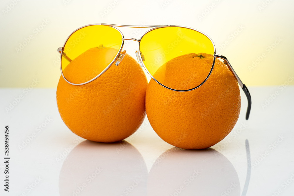 Wall mural two whole oranges on a white background in sunglasses