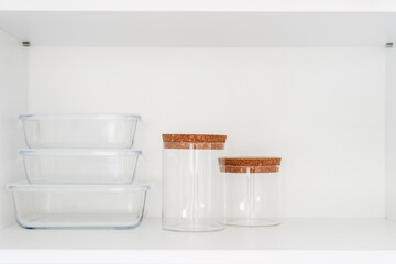 food containers and glass jars on white shelf at kitchen