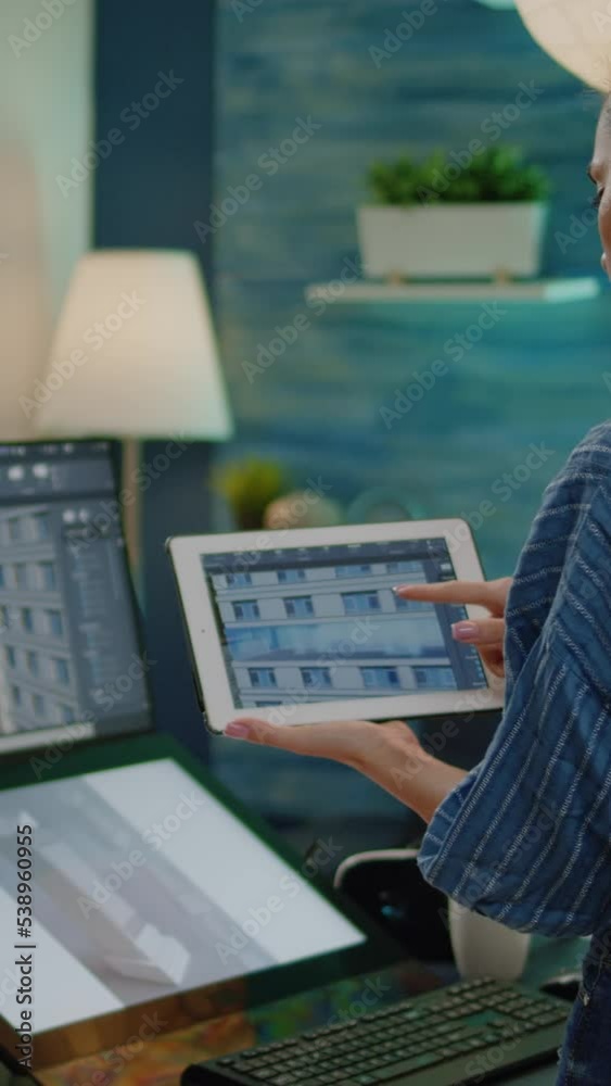 Poster vertical video: professional engineer looking at building model on tablet and computer in workplace 