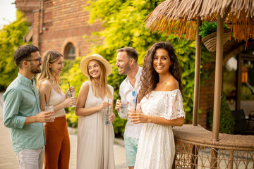 Group of young people cheering and having fun outdoors with drinks