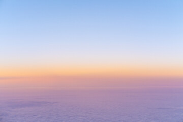 Fototapeta na wymiar Aerial view of bright yellow sunset over pink purple dense clouds with blue sky overhead, top view from an airplane. Sky Gradient. Can be used as advertising background, overlay. Travel concept.