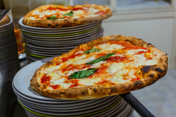 Due pizze Margherita napoletane con sugo di pomodoro, mozzarella e basilico appena sfornate e pronte per essere servite in una pizzeria napoletana