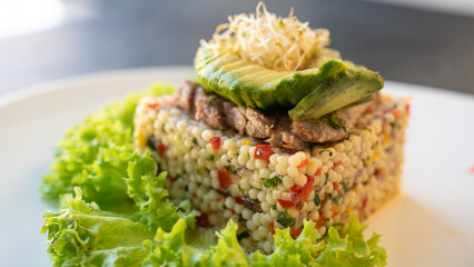 Beautiful served sago with meat, avocado and green lettuce leaves on plate. Shabbat food. Restaurant on a background.