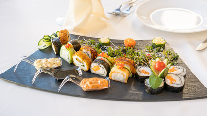 Beautiful served vegetarian sushi rolls on a plate. With natural vegetables and sauce. Black background
