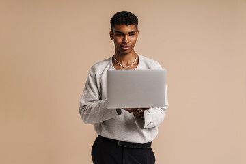 Fototapeta premium Young black man working with laptop while posing at camera
