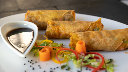Tasty Spring rolls on a white plate with fresh salad. black background. 
