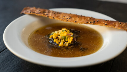 Beautiful served Onion soup. With natural vegetables, green leaves. Bread, glass and restaurant background