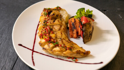 grilled fish with grilled vegetables and sause. black background