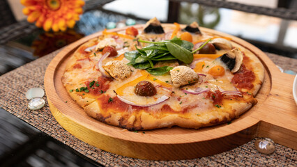 Tasty pizza on a wooden tray. With cherry tomatoes, spinach and pepper.