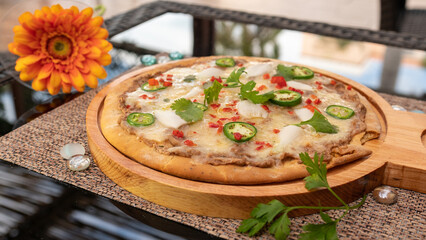 Tasty pizza on a wooden tray. With cherry tomatoes, spinach and pepper.
