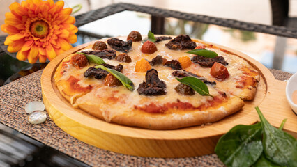 Tasty pizza on a wooden tray. With cherry tomatoes, spinach and pepper.