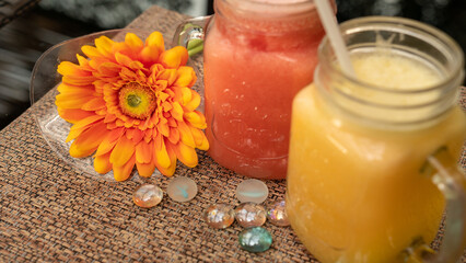 Delicious red watermelon smoothie in a tall glass.  Gerbera flower and restaurant background.