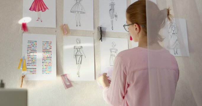 Woman fashion designer develops sketches of dresses. A seamstress is working on creating clothes.