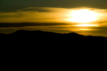tramonto siluette montagna con sole e foschia di nuvole