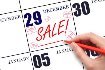 Hand writing text SALE and drawing gift boxes on calendar date December 29. Shopping Reminder