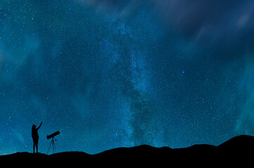 Girl silhouette stands on the hill with telescope on and looks on the  milky way galaxy. Dark...