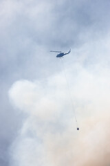 Wildfire Service Helicopter flying over BC Forest Fire and Smoke on the mountain near Hope during a hot sunny summer day. British Columbia, Canada. Natural Disaster