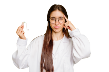 Young otorhinolaryngologist caucasian woman holding hearing aid isolated pointing temple with finger, thinking, focused on a task.
