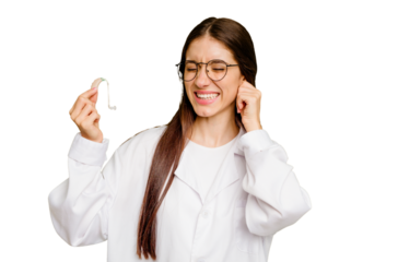 Young otorhinolaryngologist caucasian woman holding hearing aid isolated covering ears with hands.