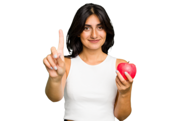 Young Indian woman holding an apple, healthy lifestyle, isolated showing number one with finger.