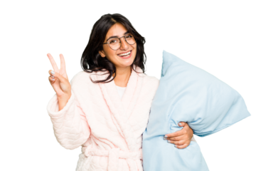 Young Indian woman wearing a pajama isolated joyful and carefree showing a peace symbol with fingers.