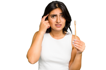 Young Indian woman holding a toothbrush isolated showing a disappointment gesture with forefinger.