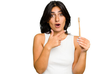 Young Indian woman holding a toothbrush isolated pointing to the side