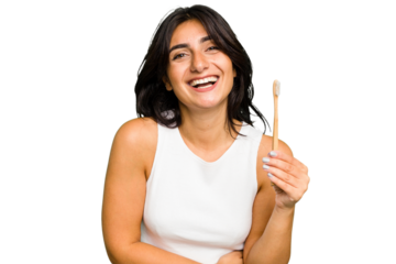 Young Indian woman holding a toothbrush isolated laughing and having fun.