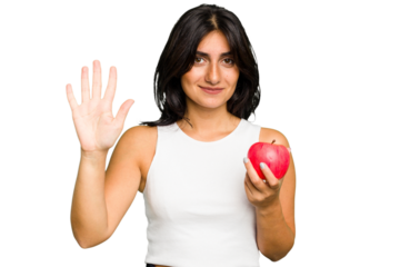 Young Indian woman holding an apple, healthy lifestyle, isolated smiling cheerful showing number five with fingers.