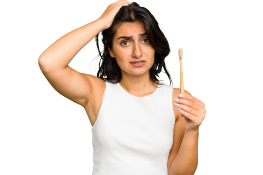 Young Indian woman holding a toothbrush isolated being shocked, she has remembered important meeting.