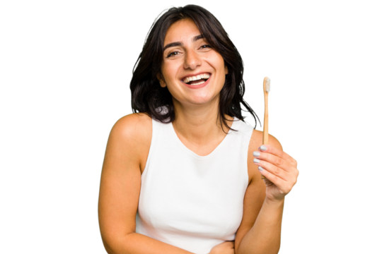Young Indian woman holding a toothbrush isolated laughing and having fun. - Powered by Adobe