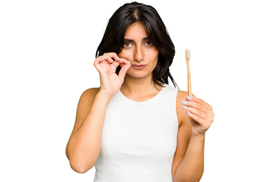 Young Indian woman holding a toothbrush isolated with fingers on lips keeping a secret.