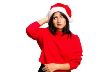 Young Indian woman celebrating Christmas wearing a santa hat isolated touching back of head, thinking and making a choice.
