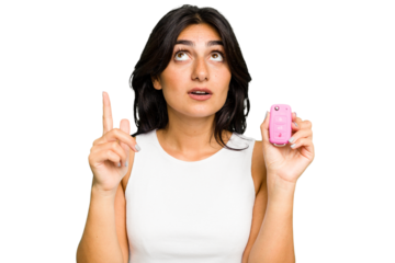 Young Indian woman holding a car keys isolated pointing upside with opened mouth.