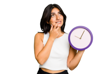Young Indian woman holding a clock isolated relaxed thinking about something looking at a copy space.