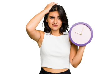 Young Indian woman holding a clock isolated being shocked, she has remembered important meeting.