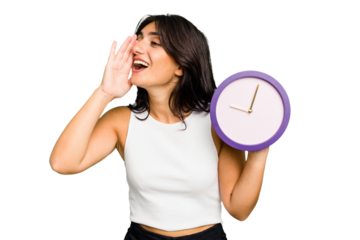 Young Indian woman holding a clock isolated shouting and holding palm near opened mouth.
