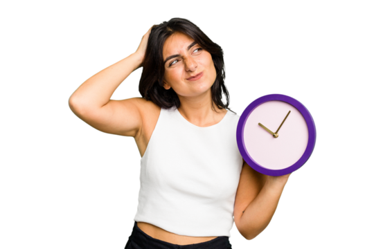 Young Indian woman holding a clock isolated touching back of head, thinking and making a choice.