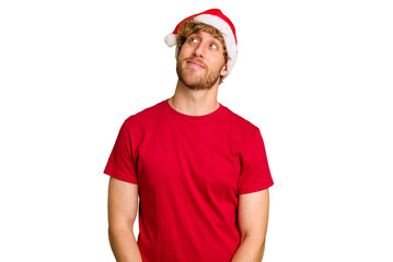 Young caucasian man wearing a Christmas Santa hat isolated on white background dreaming of achieving goals and purposes