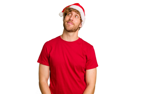 Young caucasian man wearing a Christmas Santa hat isolated on white background dreaming of achieving goals and purposes