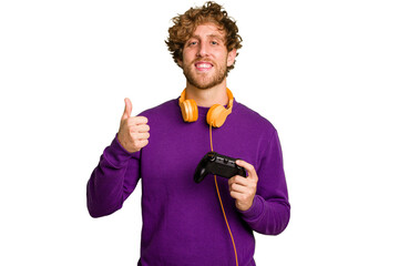 Young caucasian gamer man holding a game controller isolated on white background smiling and raising thumb up © Asier