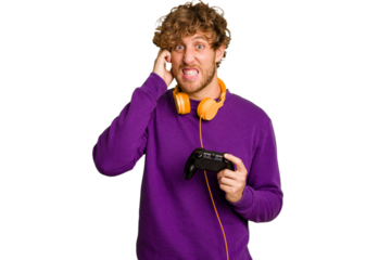 Young caucasian gamer man holding a game controller isolated on white background covering ears with hands.