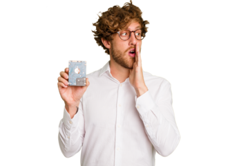 Young caucasian informatic man holding a hard drive isolated on white background is saying a secret hot braking news and looking aside