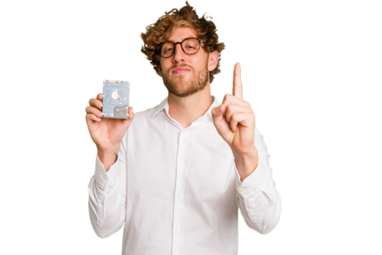 Young caucasian informatic man holding a hard drive isolated on white background showing number one with finger. - Powered by Adobe
