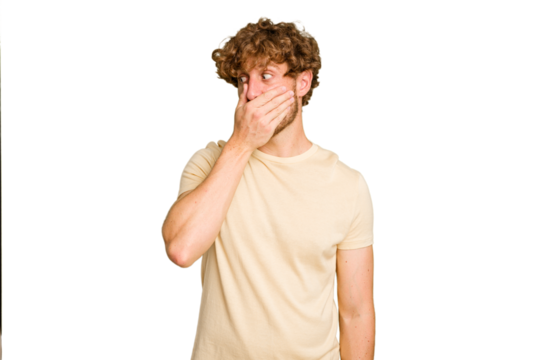 Young caucasian man isolated on green chroma background thoughtful looking to a copy space covering mouth with hand.