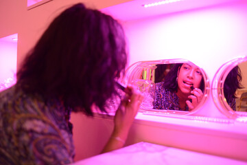 southeast asian pretty young woman empowering making up lipstick at the mirror